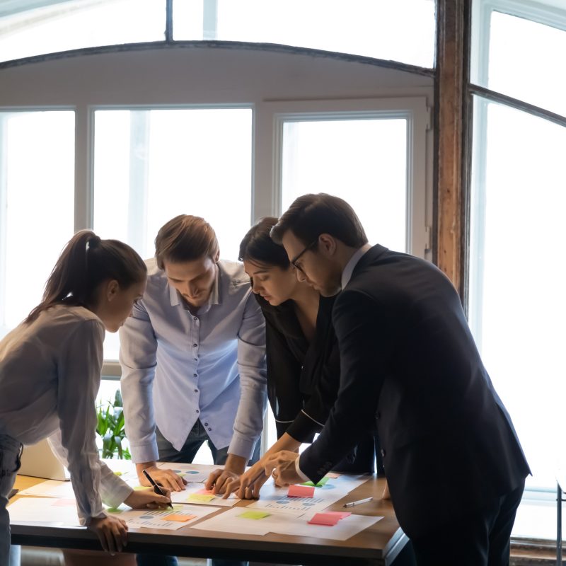 Millennial woman tutor expert consultant teaching students colleagues interns to work with statistic reports on practical training, multiethnic young specialists designers engineers developing project
