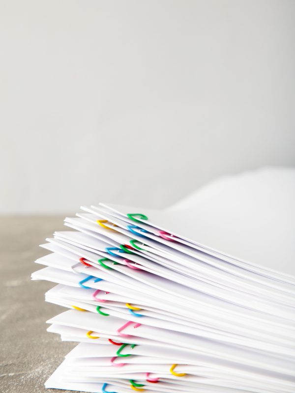 Stack of white paper with clips on grey background. Top view