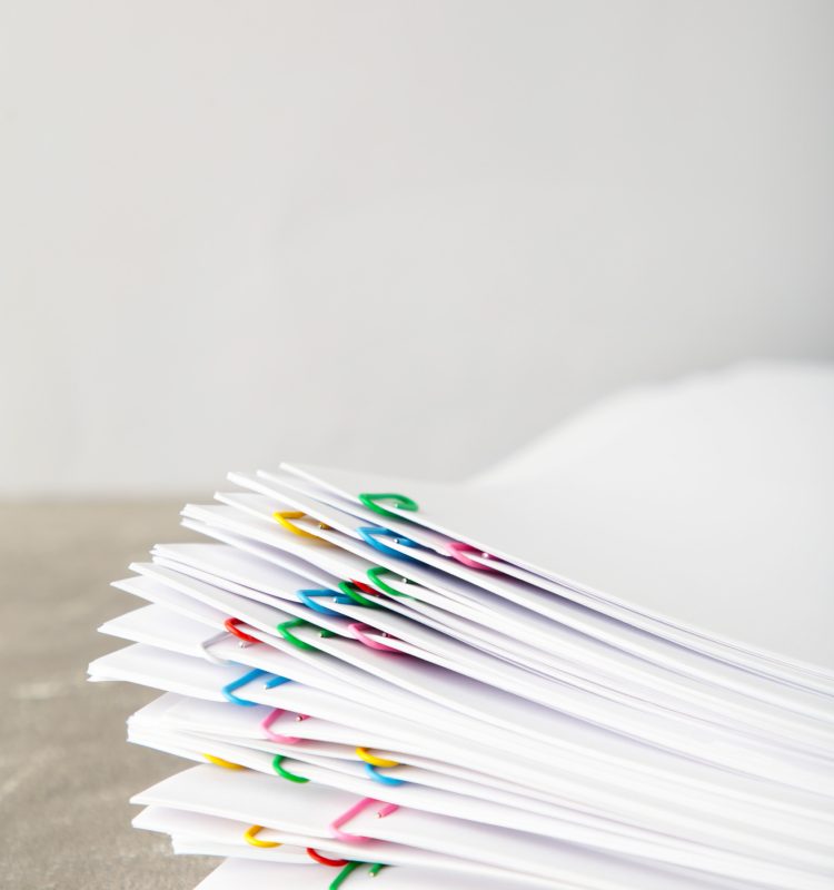 Stack of white paper with clips on grey background. Top view